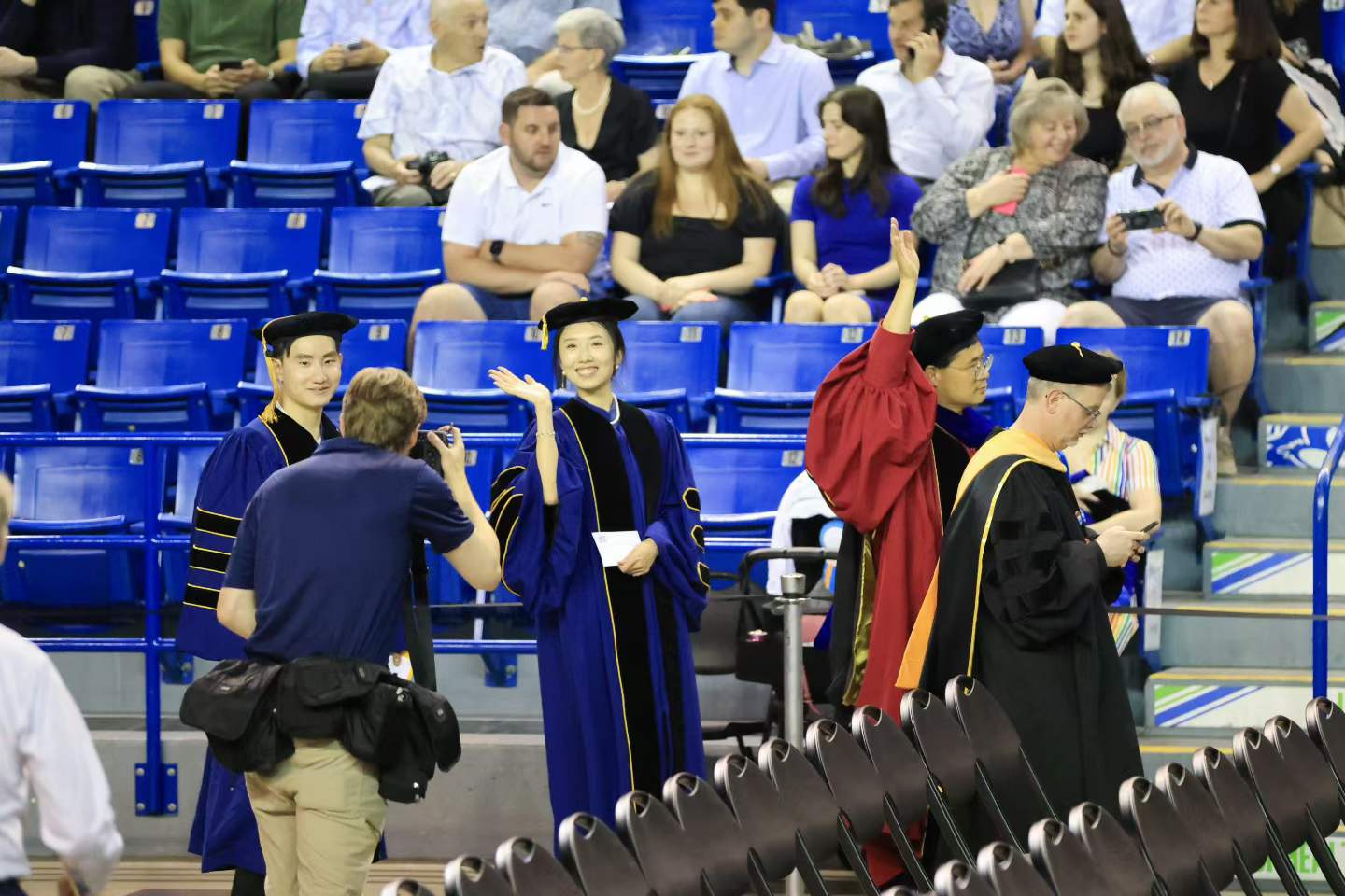 Chuchu Chen waving in doctoral regalia at her graduation ceremony.